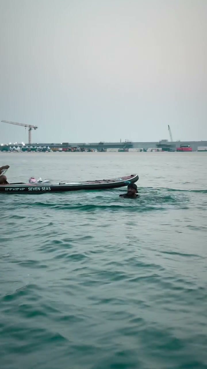 Paddleboarder gliding across calm water toward the Dubai coastline