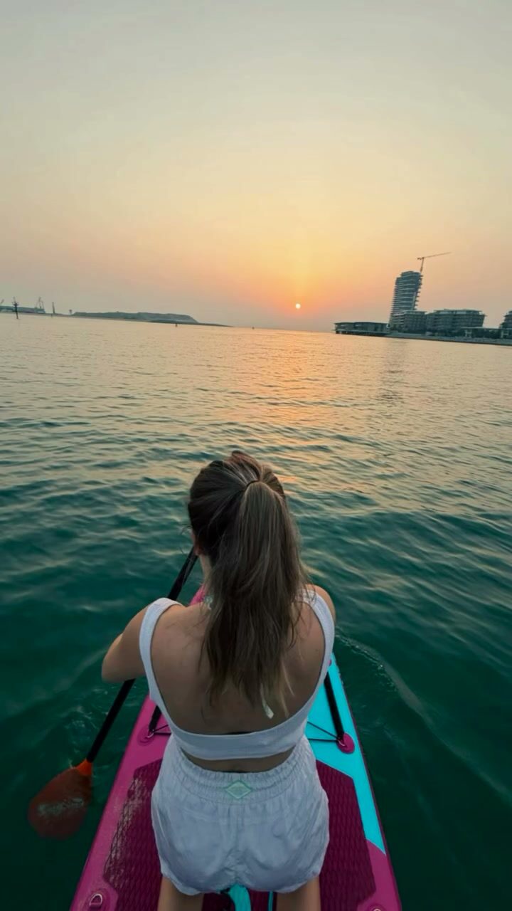 Paddler heading toward the sunset over the Dubai skyline